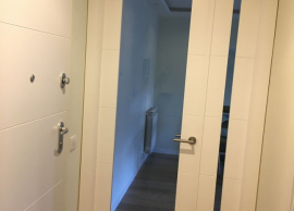 Sustitución de puerta ciega, por una puerta de cristal de arriba a abajo con luna al fuego (alta resistencia) y peinazos laterales en madera lacada en blanco